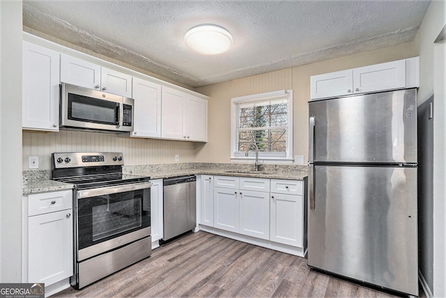 kitchen featuring appliances with stainless steel finishes, dark hardwood / wood-style flooring, a textured ceiling, sink, and white cabinetry