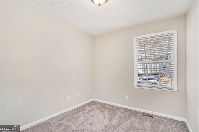 carpeted empty room with a textured ceiling