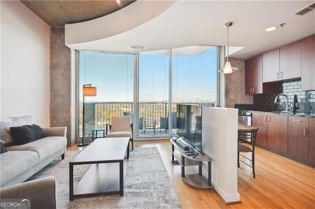 living room featuring light hardwood / wood-style flooring, expansive windows, and sink