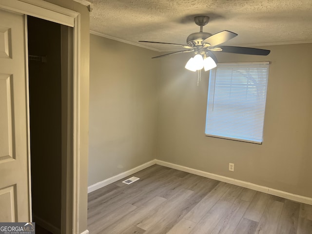 spare room with a textured ceiling, light hardwood / wood-style floors, ceiling fan, and crown molding