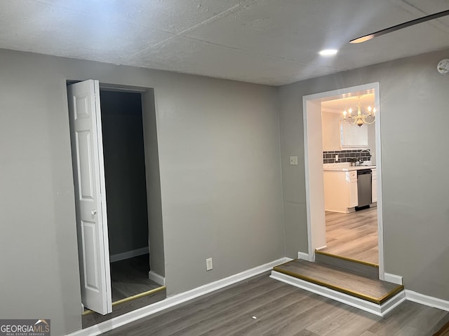 spare room featuring a notable chandelier and wood-type flooring