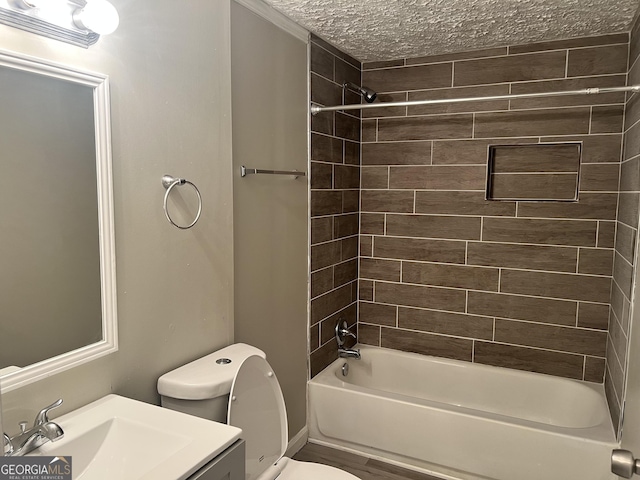 full bathroom featuring vanity, a textured ceiling, tiled shower / bath combo, hardwood / wood-style floors, and toilet