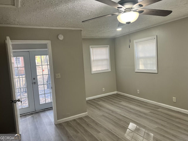 spare room featuring french doors, a textured ceiling, light hardwood / wood-style flooring, and crown molding