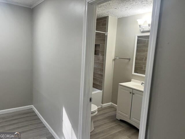 full bathroom featuring vanity, a textured ceiling, wood-type flooring, toilet, and tiled shower / bath