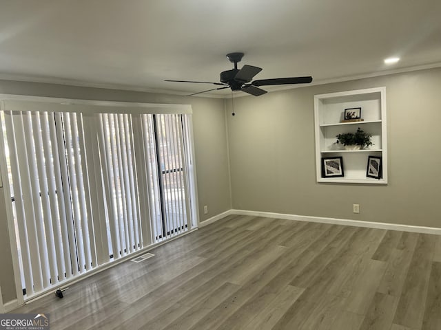 empty room featuring ceiling fan, hardwood / wood-style floors, and built in features