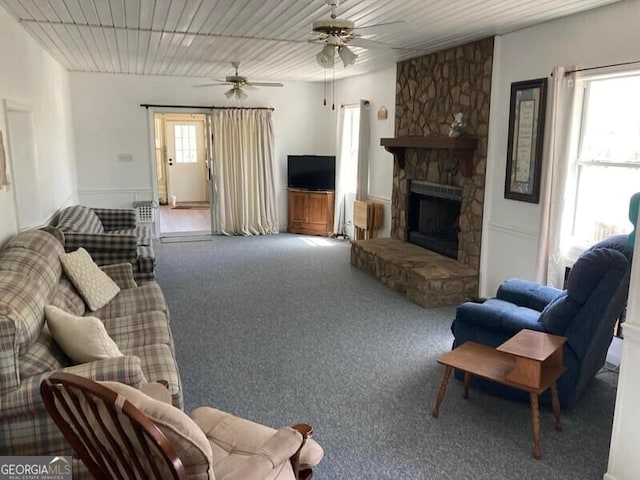 carpeted living room featuring a fireplace, ceiling fan, and plenty of natural light