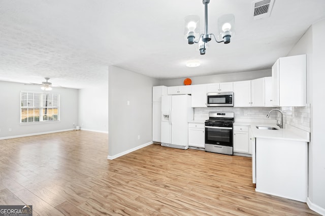 kitchen featuring white cabinetry, sink, hanging light fixtures, stainless steel appliances, and light hardwood / wood-style floors