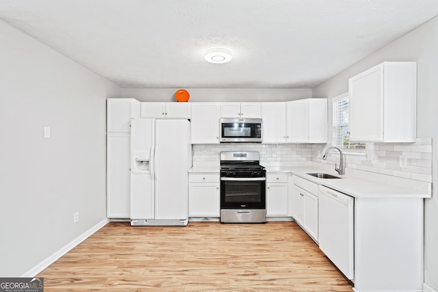 kitchen featuring white cabinets, sink, decorative backsplash, light wood-type flooring, and appliances with stainless steel finishes