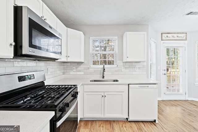 kitchen with appliances with stainless steel finishes, light wood-type flooring, white cabinetry, and plenty of natural light