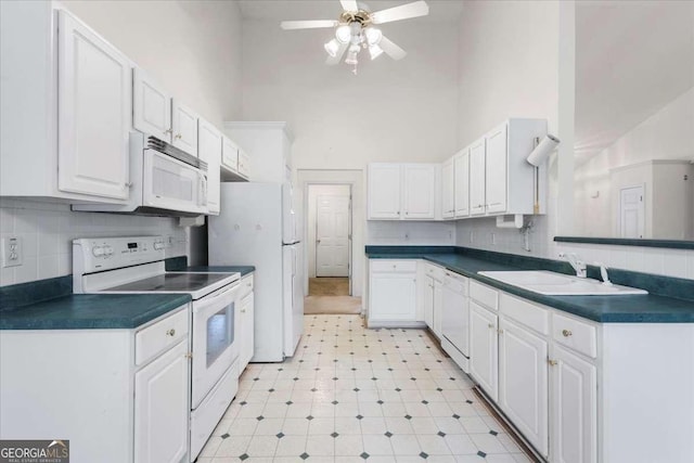 kitchen with ceiling fan, sink, a high ceiling, white appliances, and white cabinetry