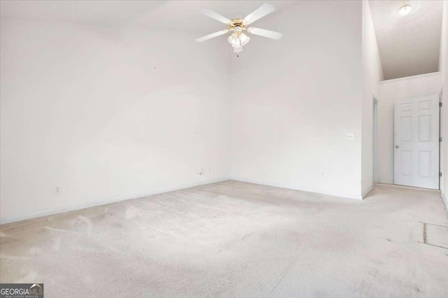 spare room with light carpet, ceiling fan, and high vaulted ceiling