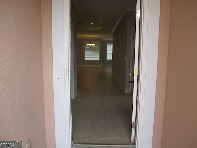 hallway featuring a notable chandelier and dark tile patterned flooring