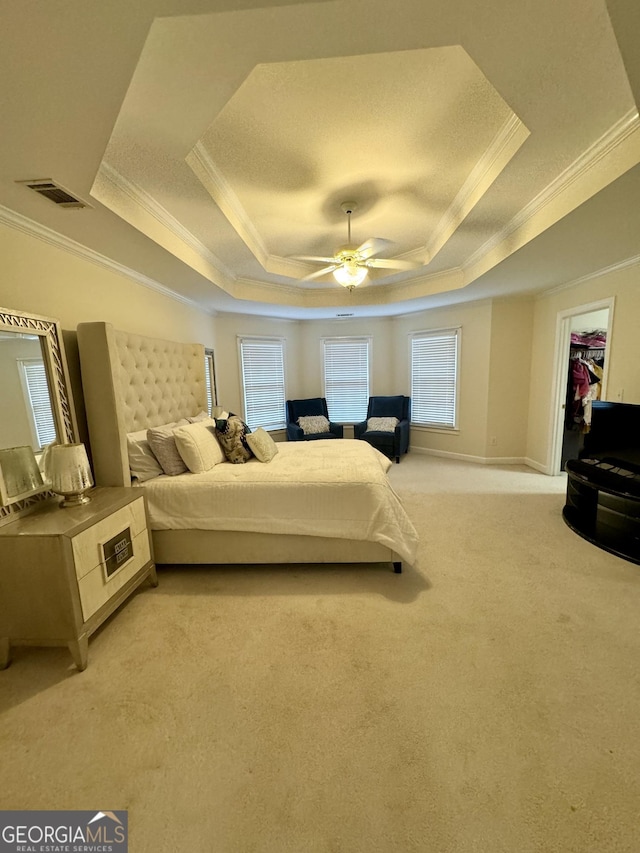 bedroom with a raised ceiling, ceiling fan, a spacious closet, light colored carpet, and a closet