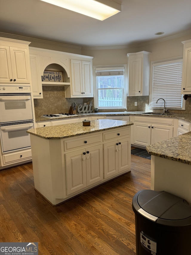 kitchen with white cabinetry, sink, light stone counters, and white appliances