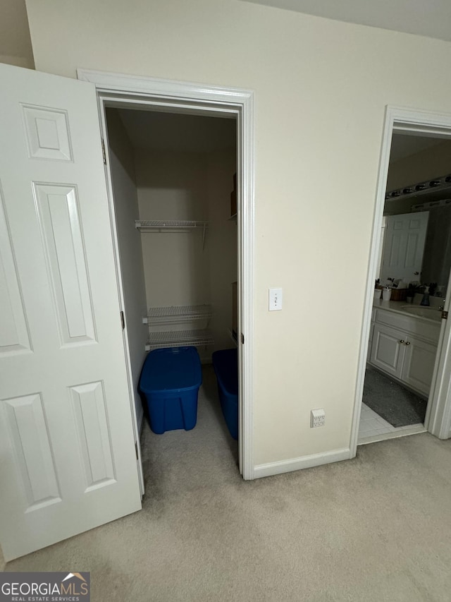 unfurnished bedroom with light colored carpet, a spacious closet, connected bathroom, and a closet