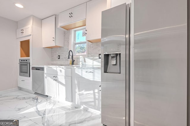 kitchen with white cabinets, sink, light stone countertops, appliances with stainless steel finishes, and tasteful backsplash