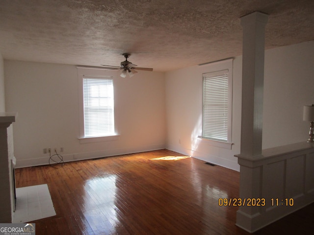 unfurnished living room featuring wood-type flooring, a textured ceiling, ornate columns, and ceiling fan