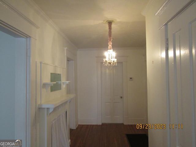 hallway with crown molding, dark wood-type flooring, and an inviting chandelier