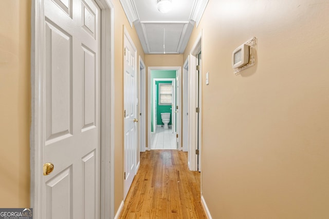 corridor with ornamental molding and light wood-type flooring