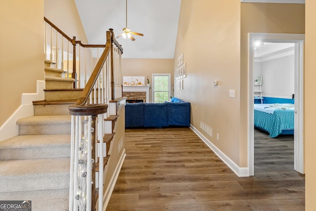 staircase featuring lofted ceiling, hardwood / wood-style floors, and ceiling fan