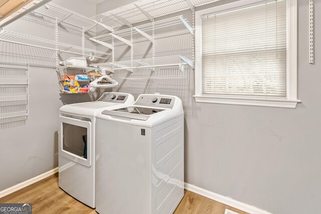 washroom featuring light wood-type flooring, baseboards, laundry area, and washing machine and clothes dryer