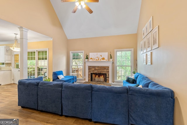 living room featuring a stone fireplace, ornate columns, high vaulted ceiling, ceiling fan, and hardwood / wood-style floors