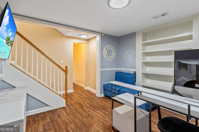 home office featuring visible vents, built in features, baseboards, and wood finished floors