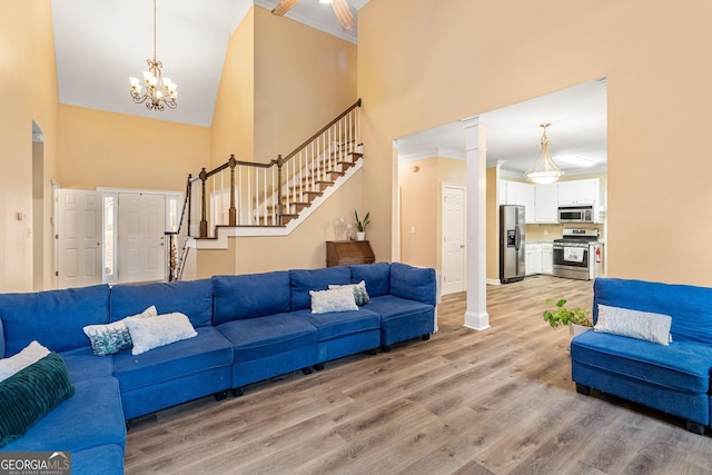 living room with crown molding, a chandelier, light hardwood / wood-style flooring, and a high ceiling