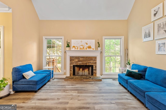 living room with lofted ceiling, a healthy amount of sunlight, a fireplace, and light hardwood / wood-style flooring