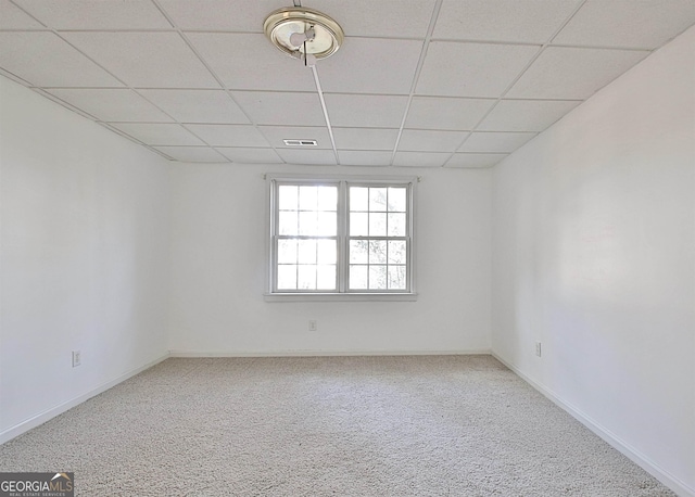 spare room with carpet, a paneled ceiling, visible vents, and baseboards