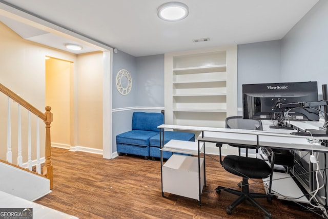 office space featuring wood-type flooring and built in shelves