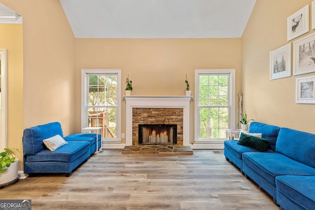 living room with visible vents, a fireplace, lofted ceiling, and wood finished floors