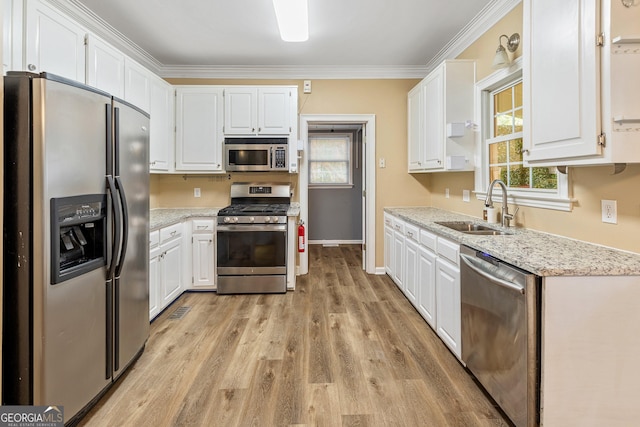 kitchen with a sink, appliances with stainless steel finishes, white cabinets, and ornamental molding