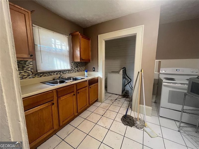 kitchen with light tile patterned flooring, washer / dryer, electric stove, and backsplash