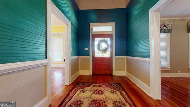 doorway with hardwood / wood-style floors and ornamental molding