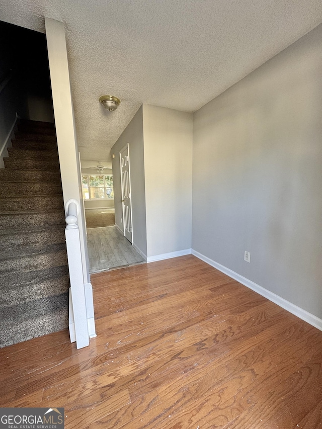 stairway with hardwood / wood-style flooring and a textured ceiling