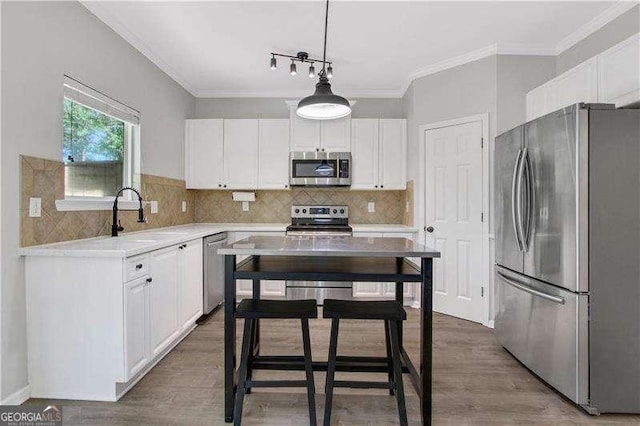 kitchen featuring decorative light fixtures, white cabinetry, sink, and appliances with stainless steel finishes