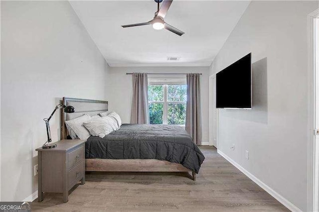 bedroom featuring light hardwood / wood-style floors, vaulted ceiling, and ceiling fan