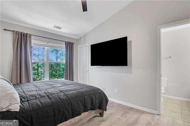 bedroom featuring ceiling fan, lofted ceiling, ensuite bathroom, and light hardwood / wood-style flooring