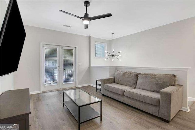 living room featuring hardwood / wood-style floors, ceiling fan with notable chandelier, french doors, and ornamental molding