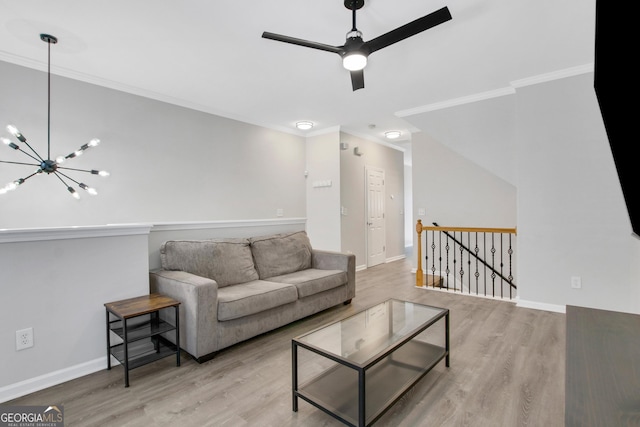 living room featuring baseboards, wood finished floors, ceiling fan with notable chandelier, and ornamental molding