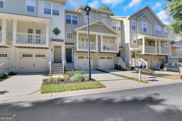 view of property with driveway, a balcony, and a garage
