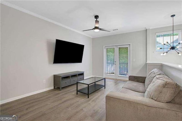 living room featuring ceiling fan, light hardwood / wood-style floors, crown molding, and french doors