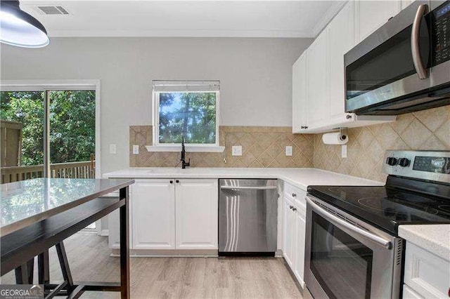 kitchen with appliances with stainless steel finishes, white cabinetry, and plenty of natural light