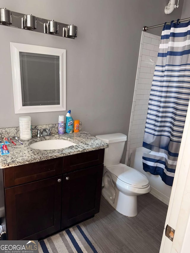 full bathroom featuring hardwood / wood-style flooring, vanity, shower / bath combo, and toilet