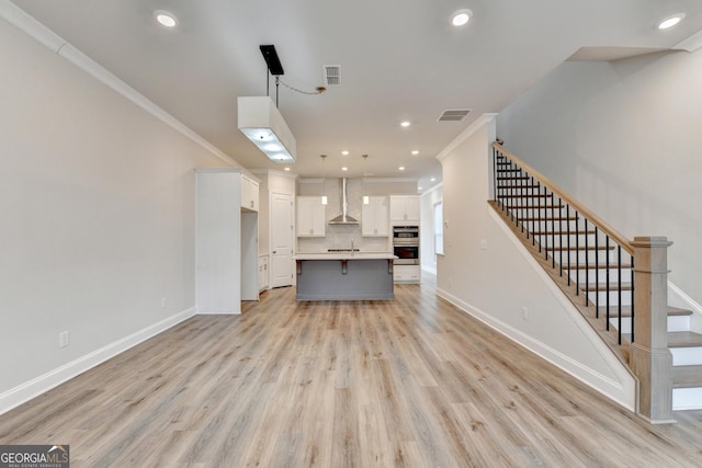 unfurnished living room featuring light hardwood / wood-style floors and crown molding