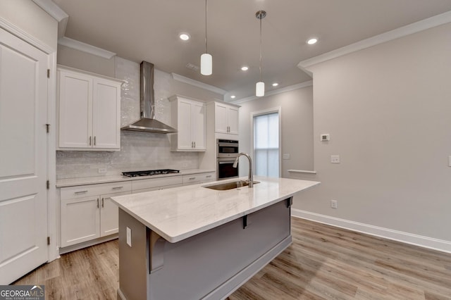 kitchen with white cabinetry, wall chimney exhaust hood, a kitchen island with sink, and gas cooktop