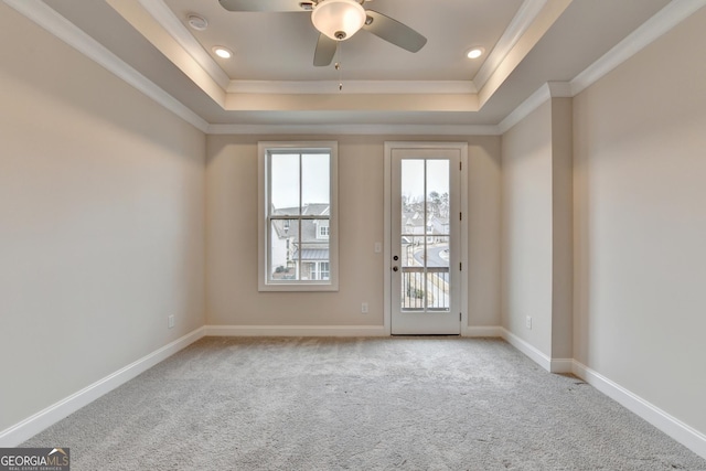 carpeted empty room featuring ceiling fan, crown molding, and a tray ceiling