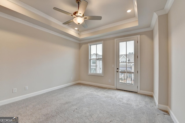 empty room featuring ceiling fan, a raised ceiling, ornamental molding, and light carpet