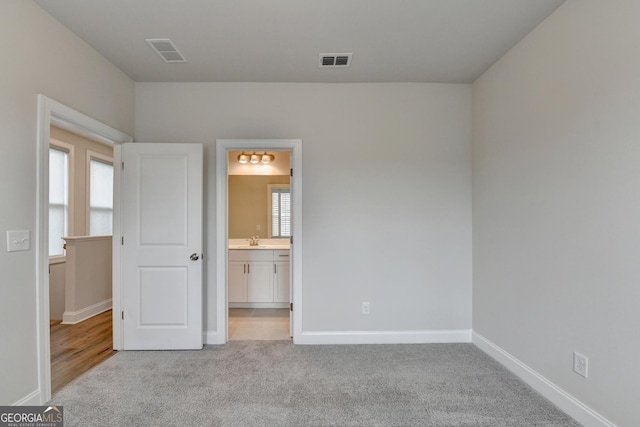 unfurnished bedroom with light colored carpet and ensuite bath